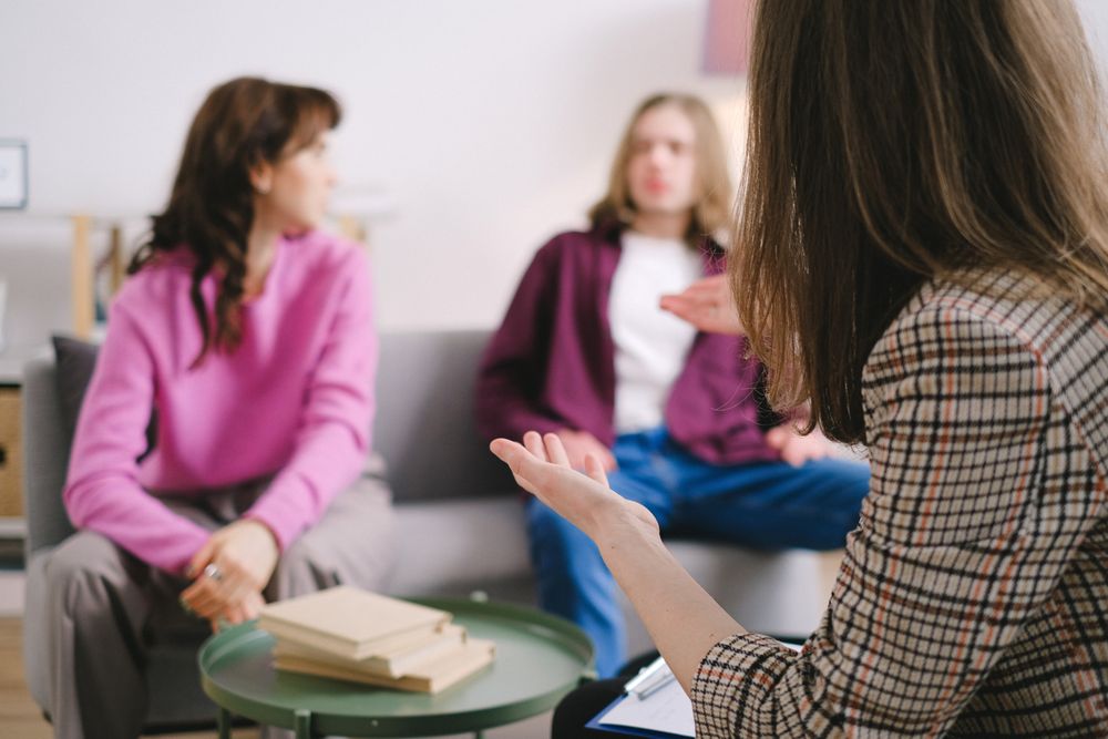 A counselor speaking with two clients during a supportive conversation